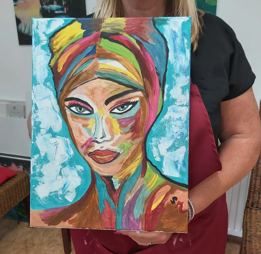 Colorful portrait painting held by a woman.
