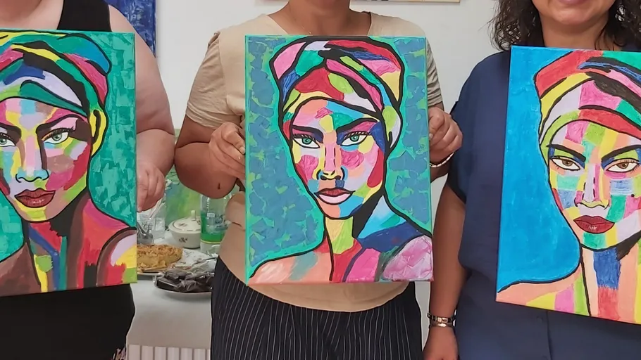 Three people holding colorful portraits indoors.