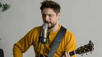 Mann singt und spielt Gitarre drinnen.