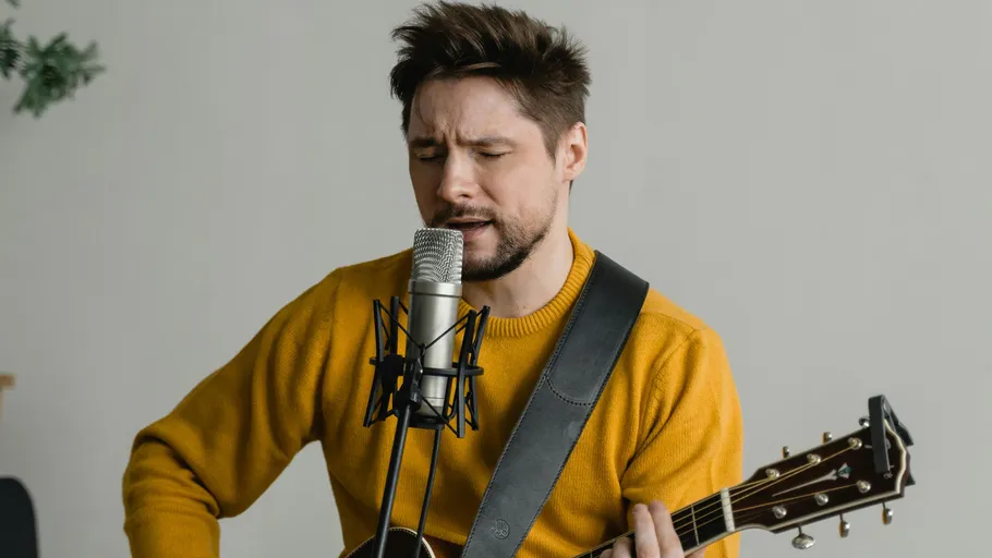 Man sings and plays guitar indoors.