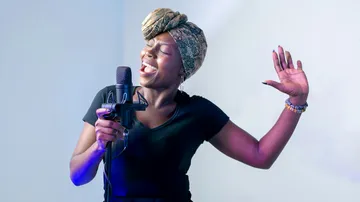 Woman sings passionately into microphone indoors.