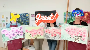 People holding cherry blossom paintings indoors.