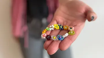 Hand hält buntes Perlenarmband.