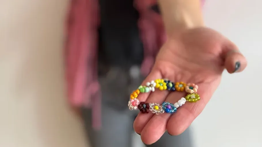 Hand hält buntes Perlenarmband.