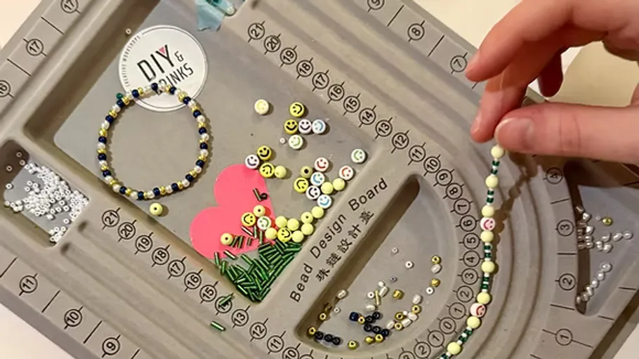 Hand arranging beads on a design board.