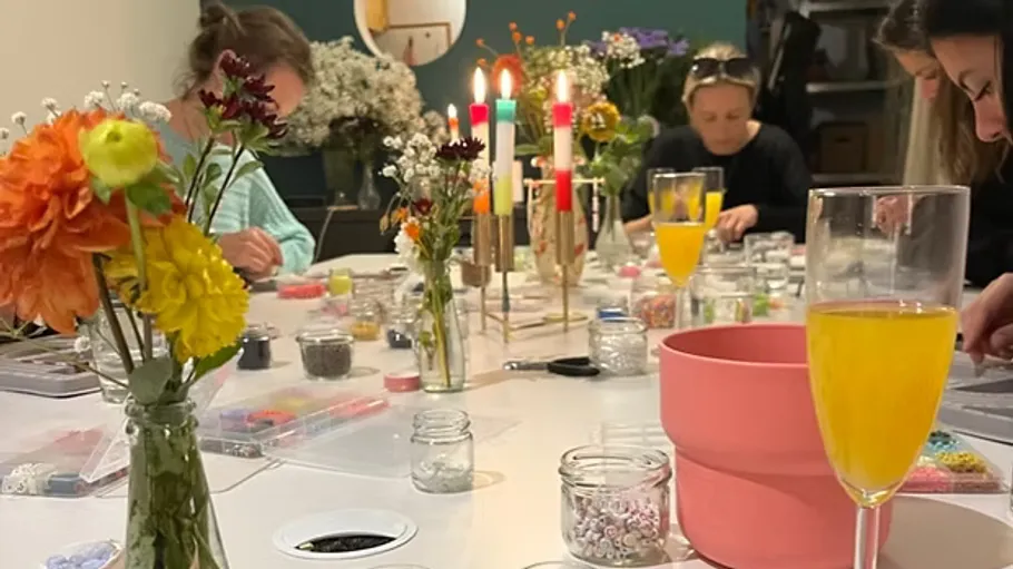 People making crafts at a table with drinks.