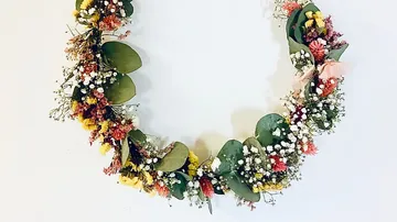 Floral wreath with green leaves against white background.