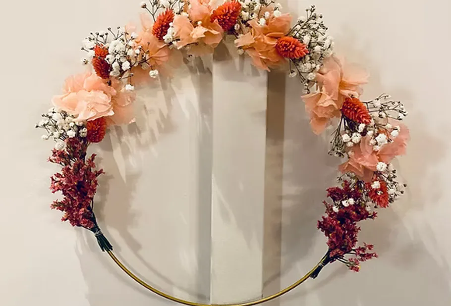 Floral wreath with pink and white flowers on wall.
