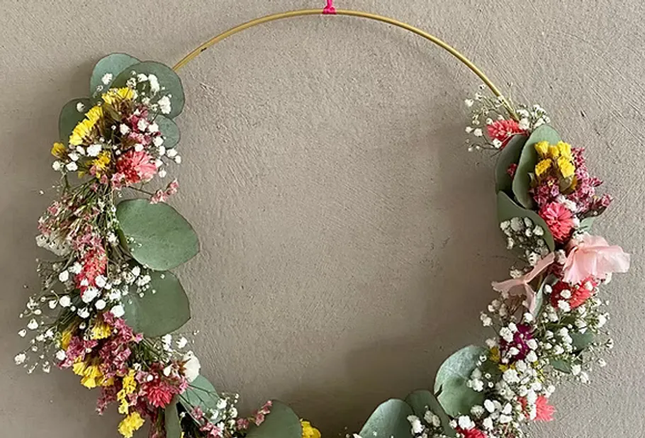 Blumenkranz mit bunten Blumen an Wand.