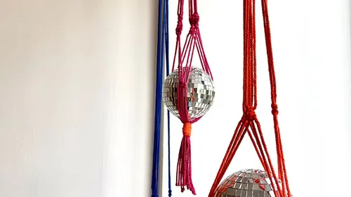 Mirrored balls hanging in colorful macramé holders.
