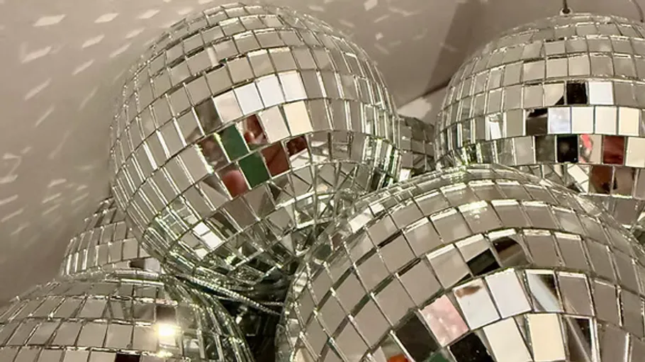 Verspiegelte Discokugeln reflektieren Licht im Cluster.
