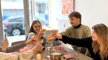 Friends toasting with drinks at a table.