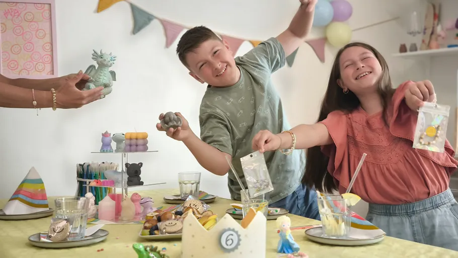 Kinder feiern an einem festlichen Partytisch.