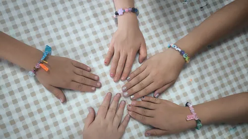 Hände mit Armbändern auf kariertem Tuch.