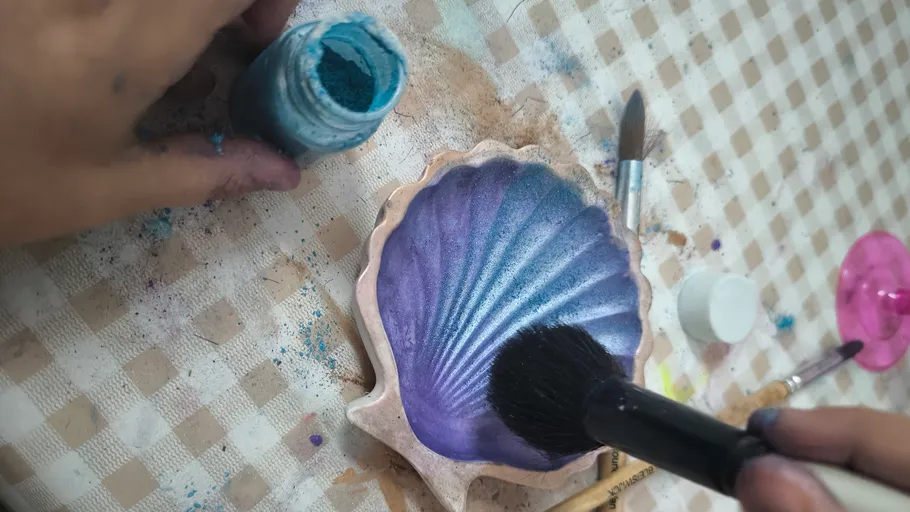 Person painting a shell on a table.