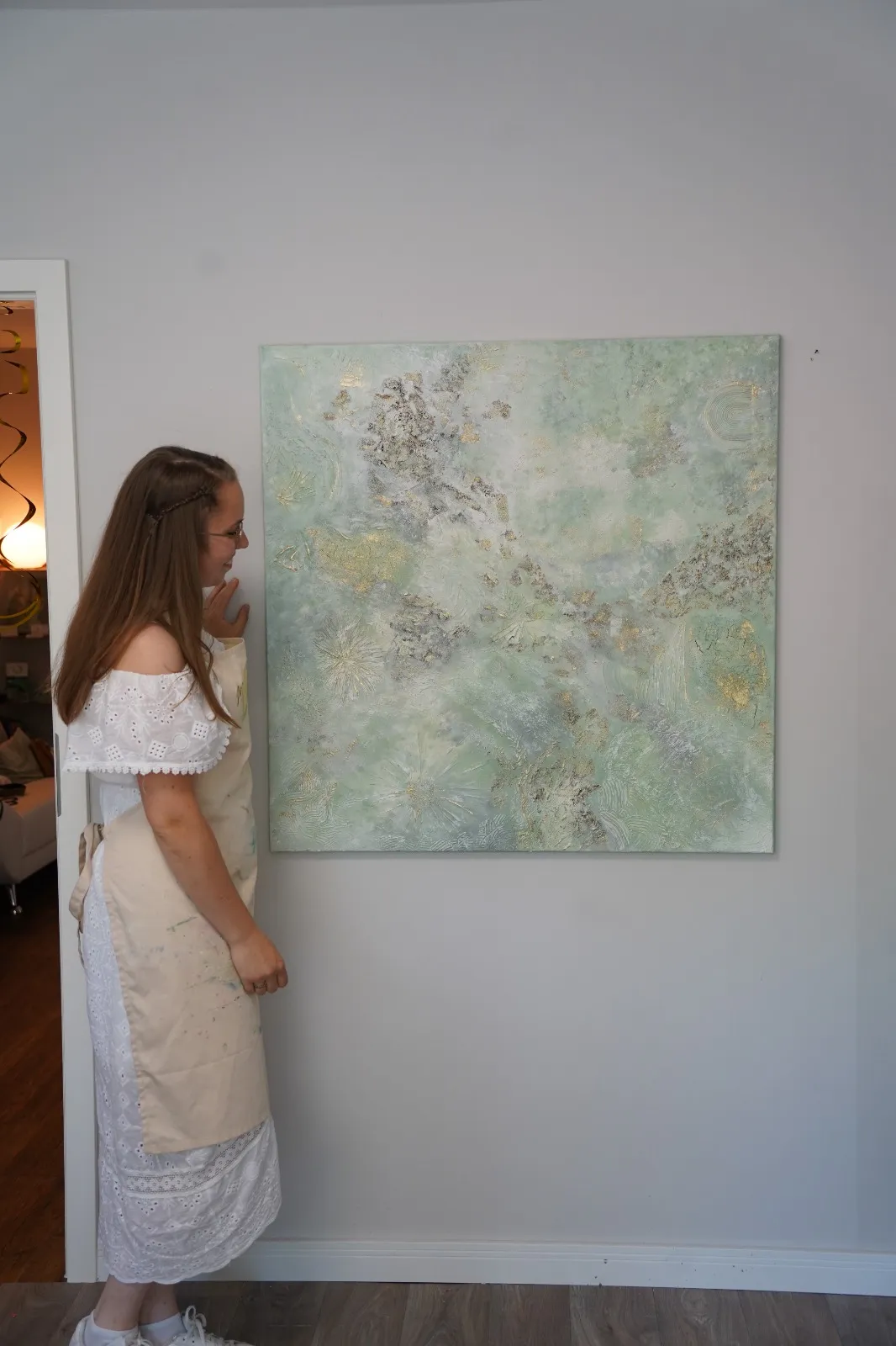 Frau betrachtet abstraktes Gemälde an Wand.