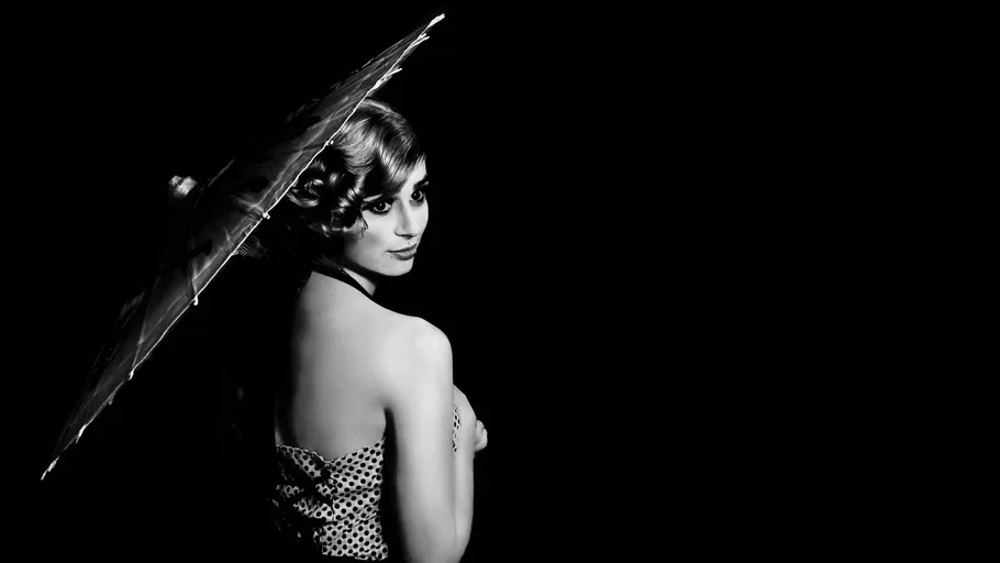Woman with parasol in black-and-white portrait.