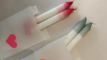 Two pairs of dipped candles in paper sleeves.