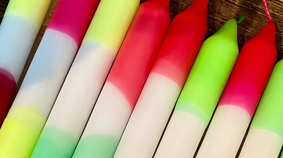 Bunte Farbverlaufskerzen auf Holzoberfläche.