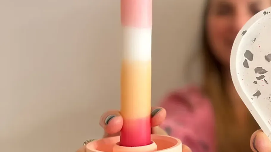 Colorful candle held by a person indoors.