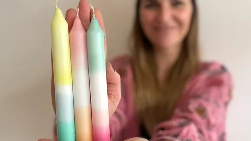 Person holding three colorful candles close up.