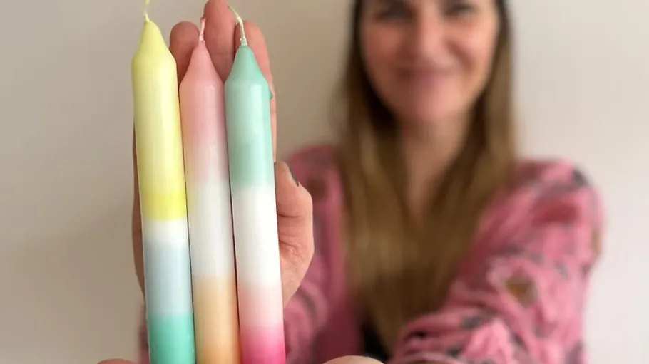Person holding three colorful candles close up.