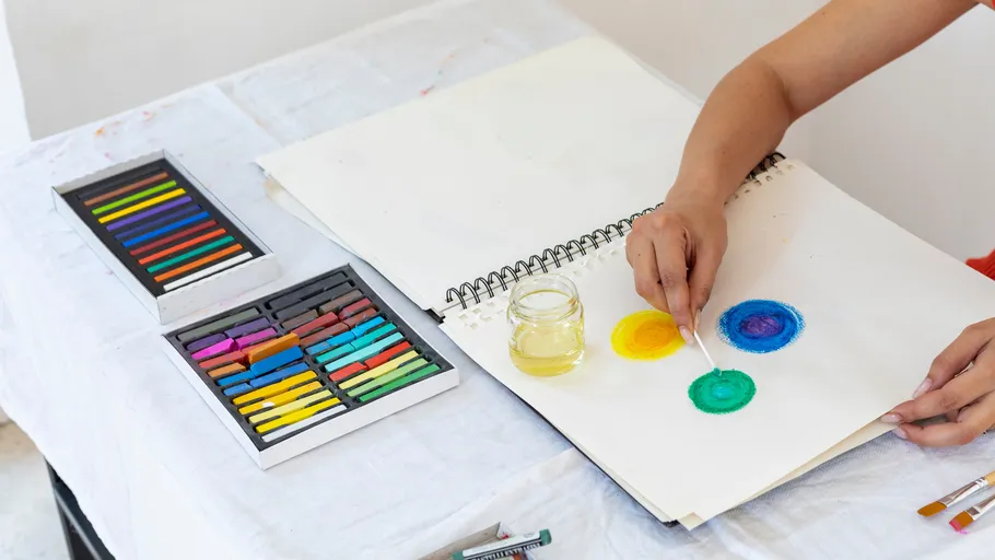 Person zeichnet bunte Kreise auf Papier.