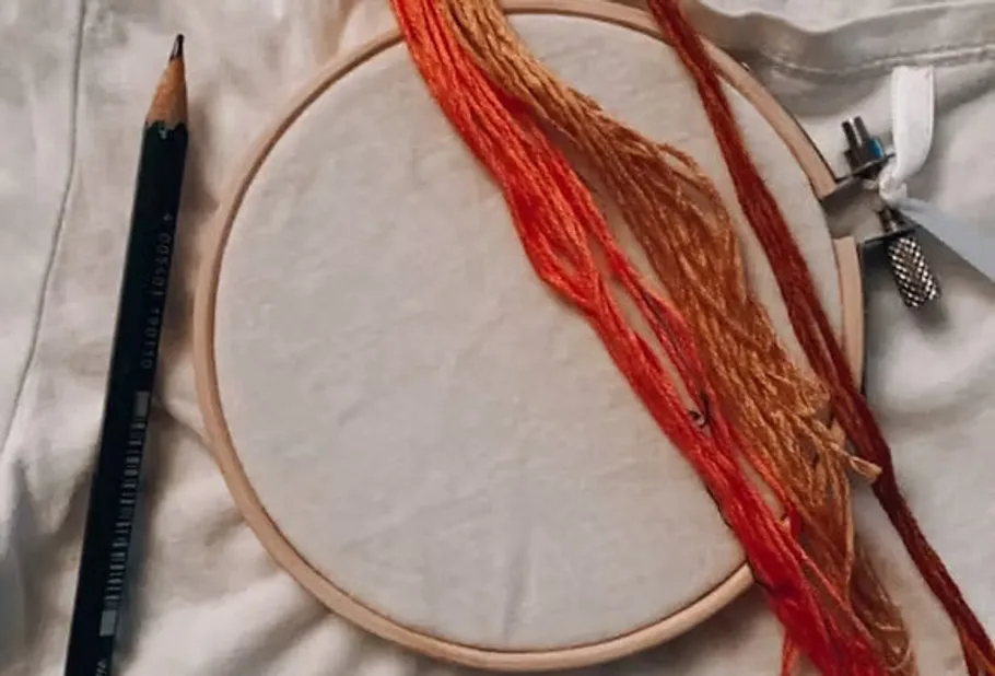 Stickrahmen mit Fäden auf Stoff.