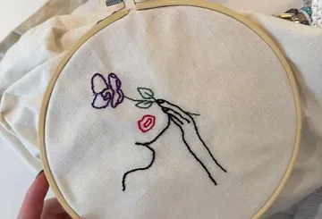 Einfache Stickerei eines Gesichts mit Blume.