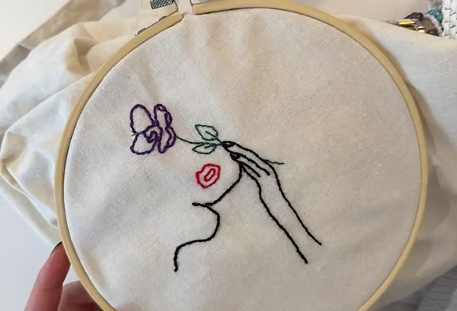 Simple embroidery of face holding flower.