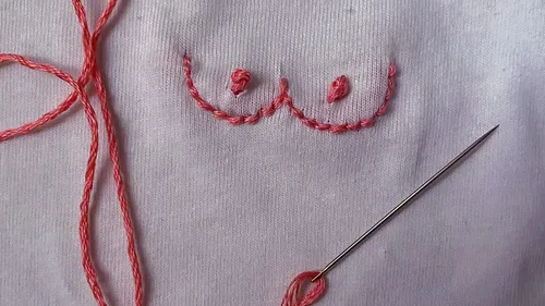 Embroidery of breasts on white fabric.