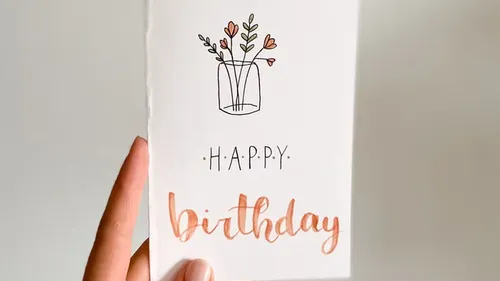 Hand holding a birthday card, floral design.