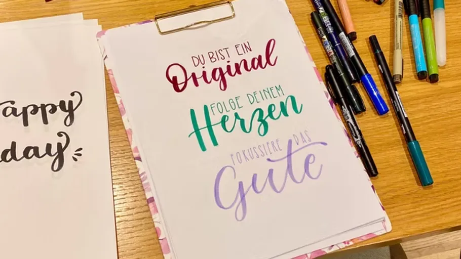Bunte Schrift auf Papier, umgeben von Markern.
