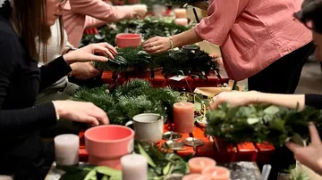 People making wreaths at a workshop table.
