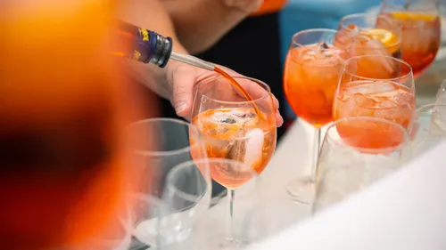 Person pouring Aperol spritz into glass.