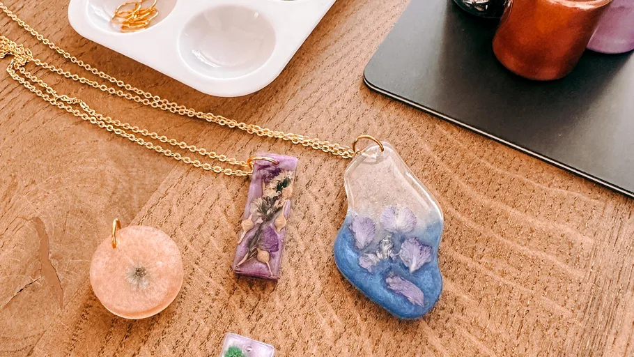 Bunte Harzschmuckstücke auf Holztisch.