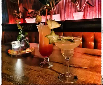 Cocktails on wooden table in dimly lit bar.
