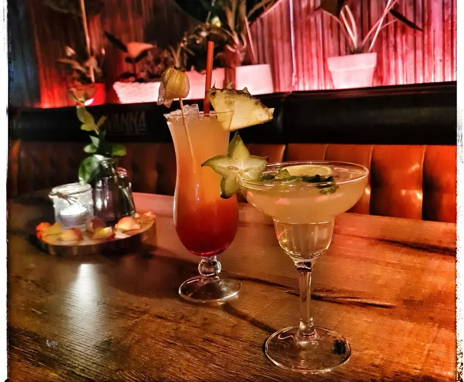 Cocktails on wooden table in dimly lit bar.