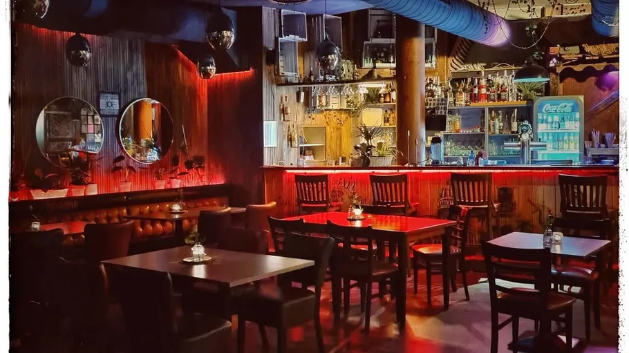 Empty bar with tables and chairs, dim lighting.