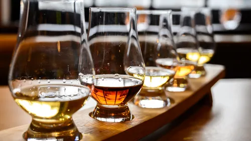 Five whiskey glasses on a wooden tray.