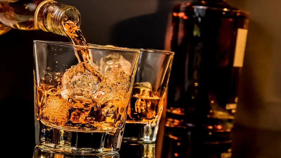 Whiskey wird in Glas mit Eis gegossen.