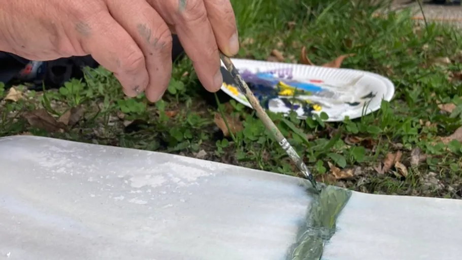 Hand painting on canvas in outdoor setting.