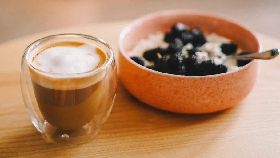 Kaffee neben Haferflocken mit Beeren.