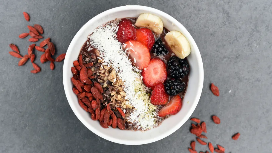 Smoothie-Schüssel mit Früchten und Toppings auf Tisch.