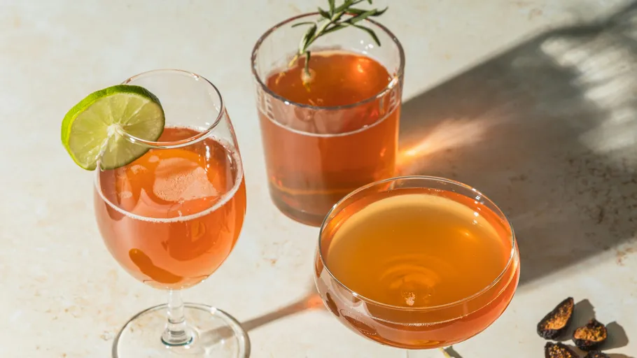 Drei Cocktails mit Garnierungen auf Tisch.