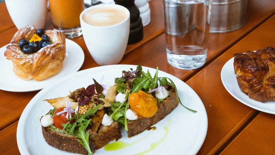 Avocado toast and pastries on wooden table.
