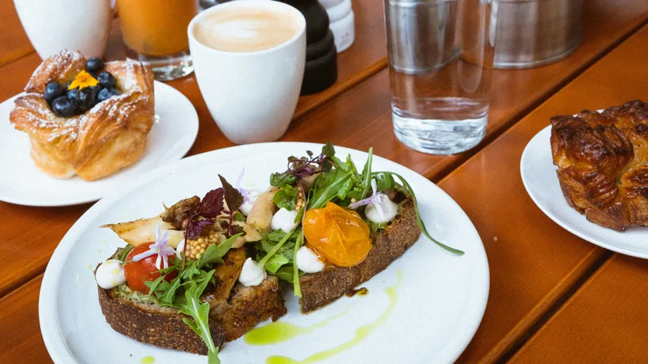 Offenes Sandwich mit Grünzeug auf Holztisch.