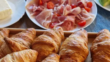 Croissants with ham and tomatoes on plates.