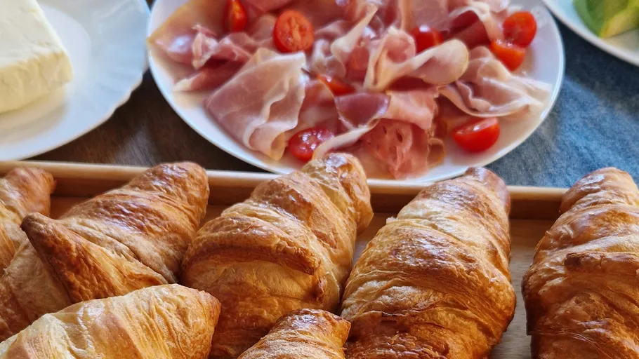 Croissants mit Schinken und Tomaten auf Tellern.