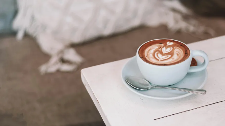 Kaffeetasse mit Latte-Art auf Tisch.